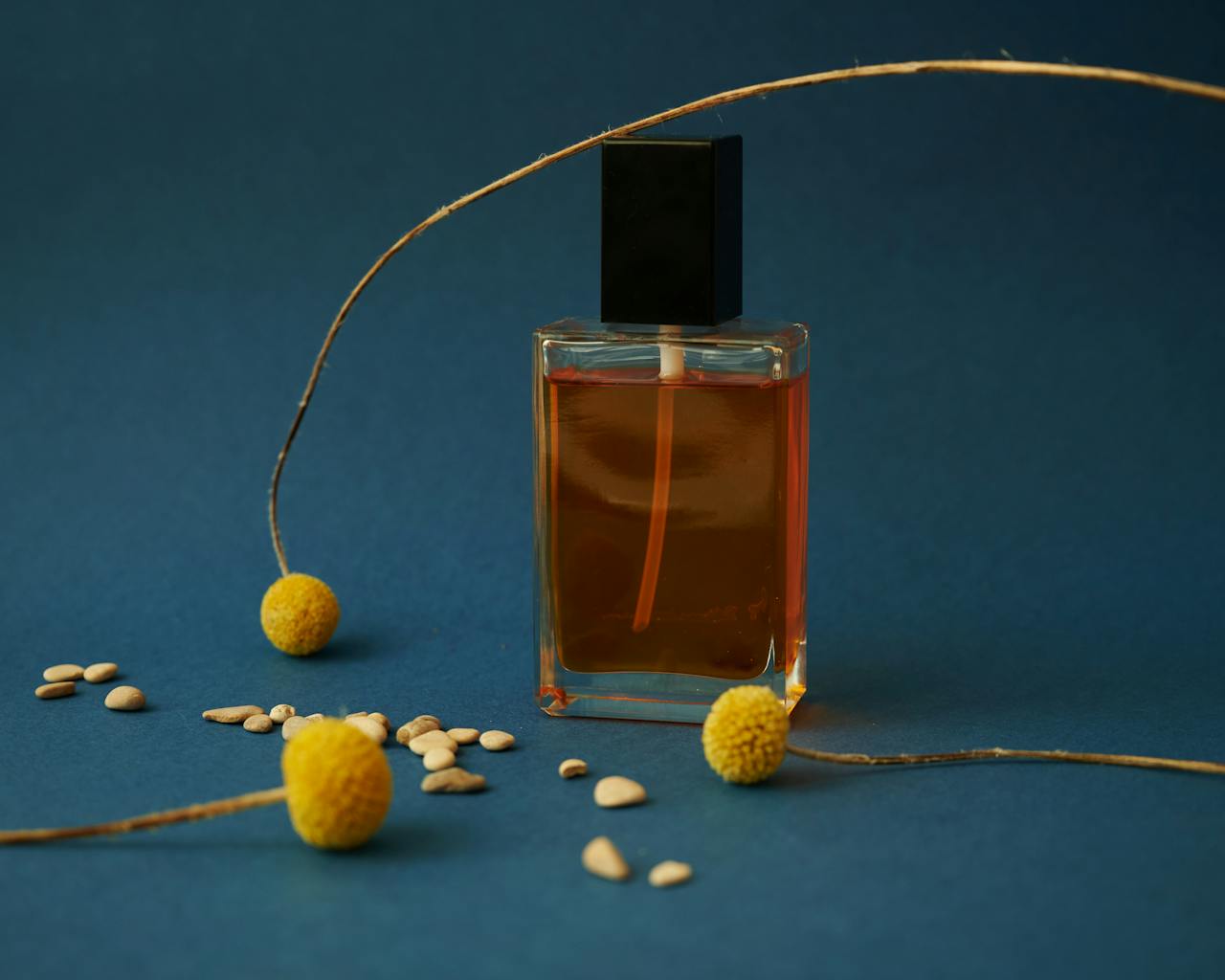 Mastering the First Impression: Your intriguing post title goes here Elegant perfume bottle with yellow flowers and seeds on a blue background. Perfect for product mockups.